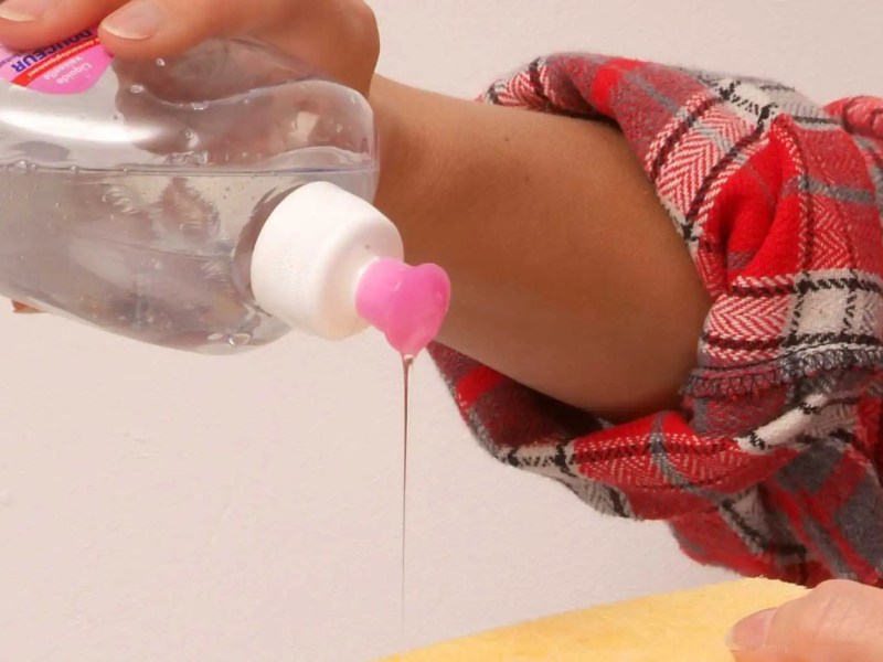 Frau gibt Spülmittel auf einen Schwamm