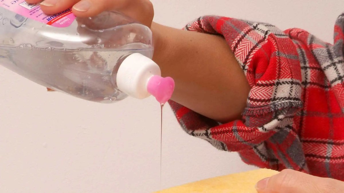 Frau gibt Spülmittel auf einen Schwamm