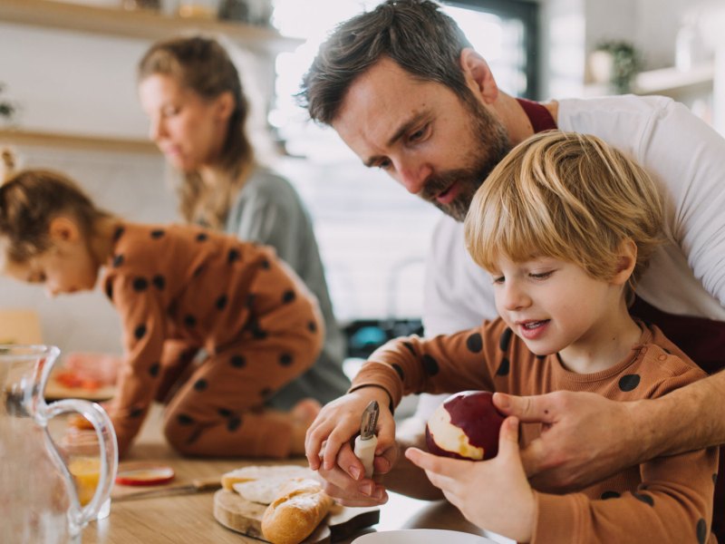 Familie bereitet gemeinsam das Frühstück zu.