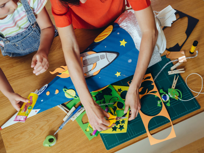 Mutter und Tochter stehen am Tisch und basteln eine Schultüte.