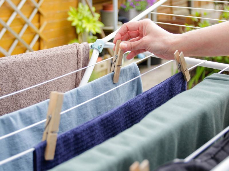 Frau hängt Wäsche auf einen Wäscheständer.