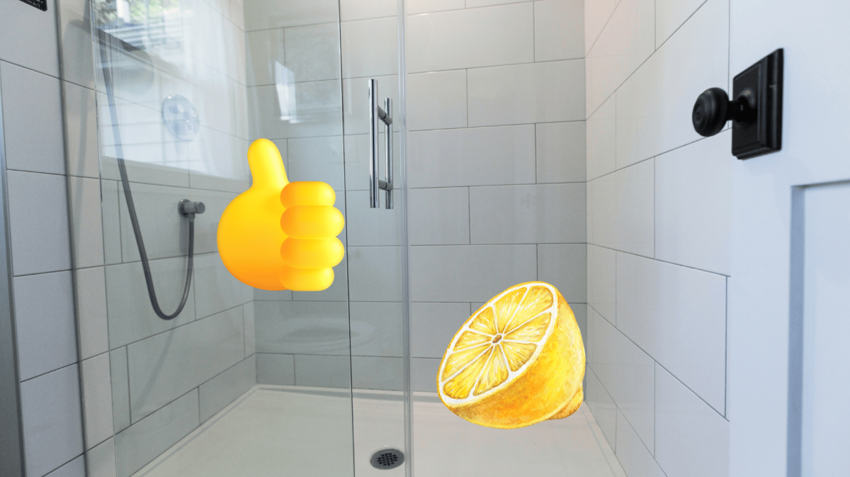 Helle geflieste Duschkabine mit Glaswand, Zitronenhälfte und Daumen-hoch-Emoji als Symbol für natürliche Reinigung.