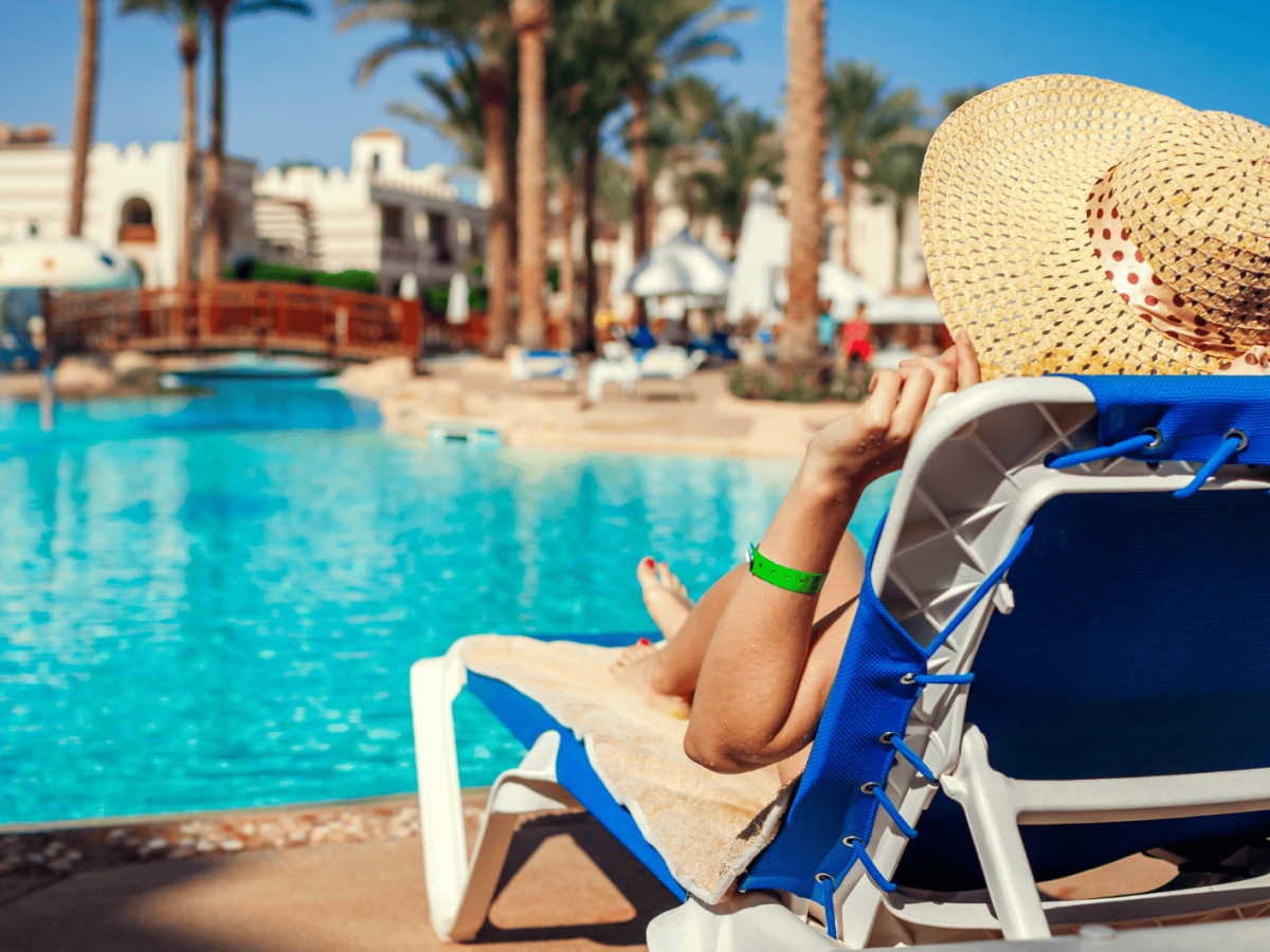 Frau relaxt auf Liege an Hotelpool.