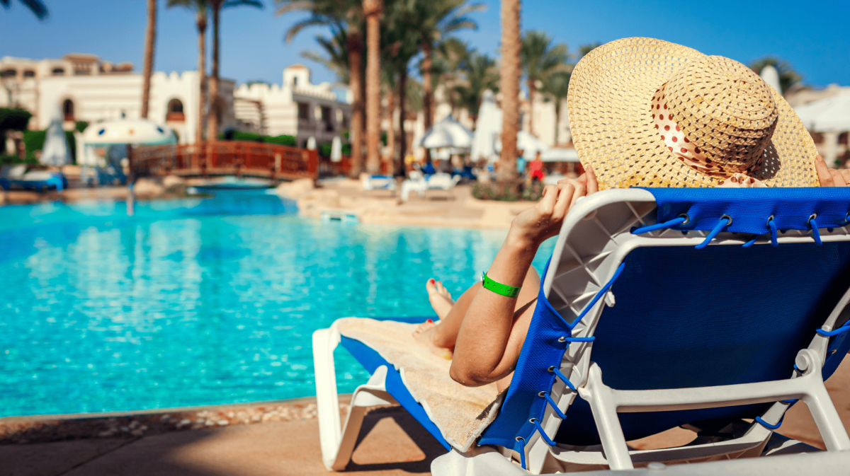 Frau relaxt auf Liege an Hotelpool.