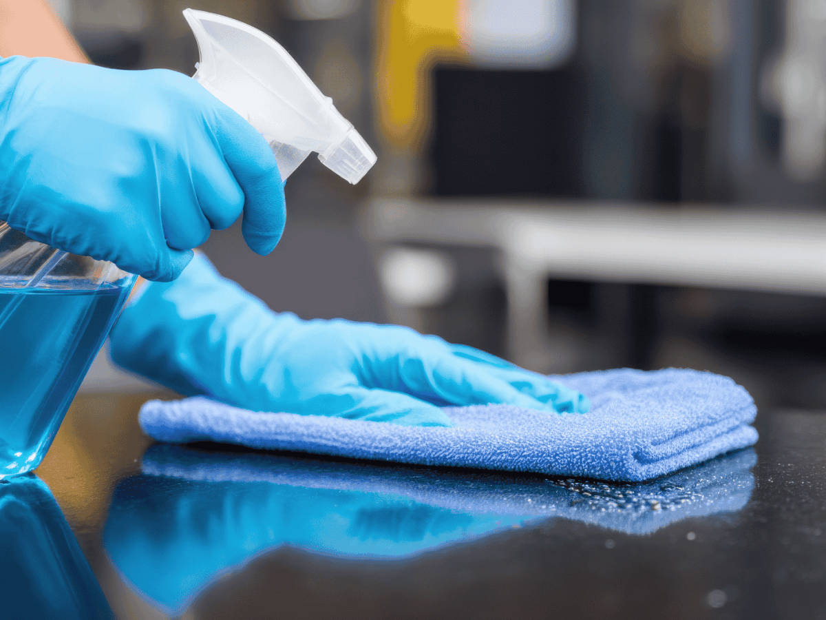 Person wischt mit Lappen &uuml;ber Oberfl&auml;che.