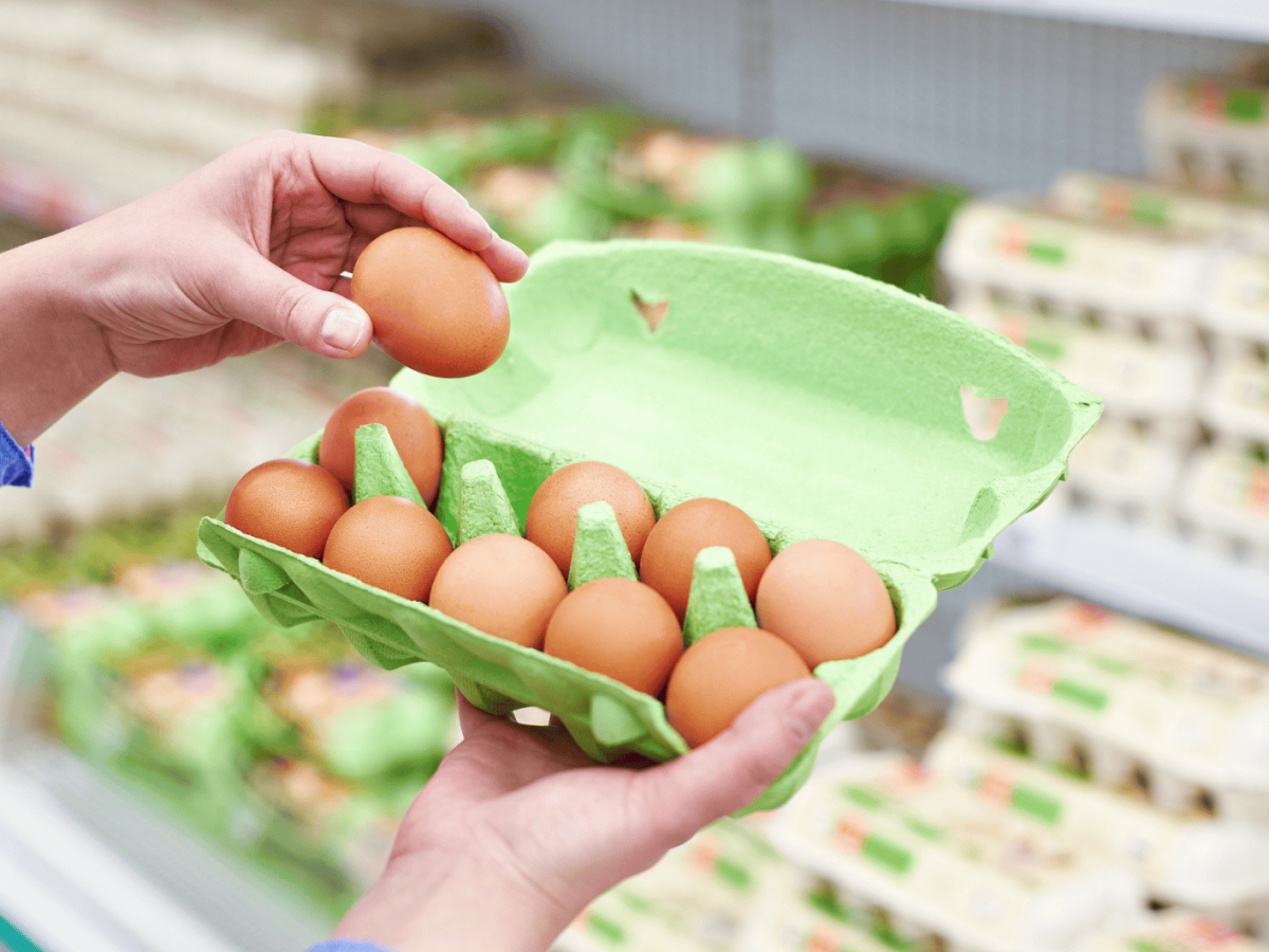 Person &ouml;ffnet Eierkarton im Supermarkt.