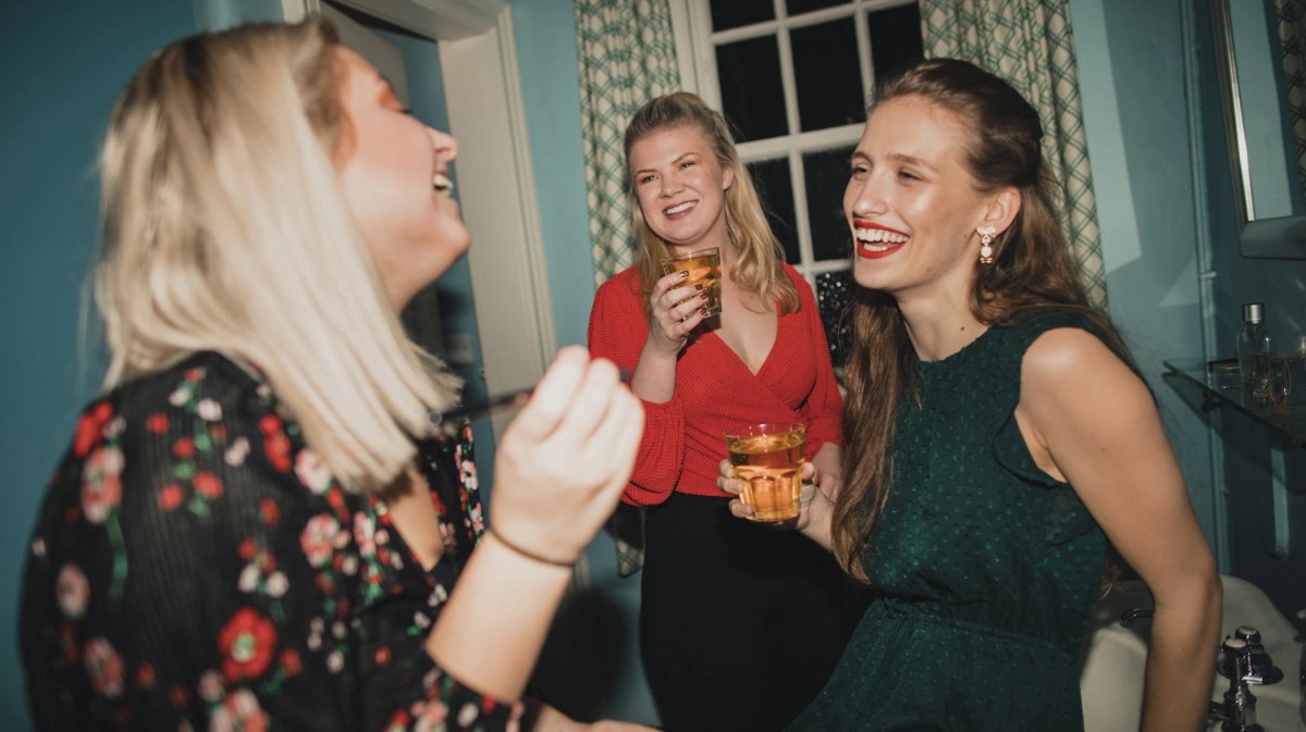 Drei Freundinnen lachen und machen sich im Badezimmer fertig