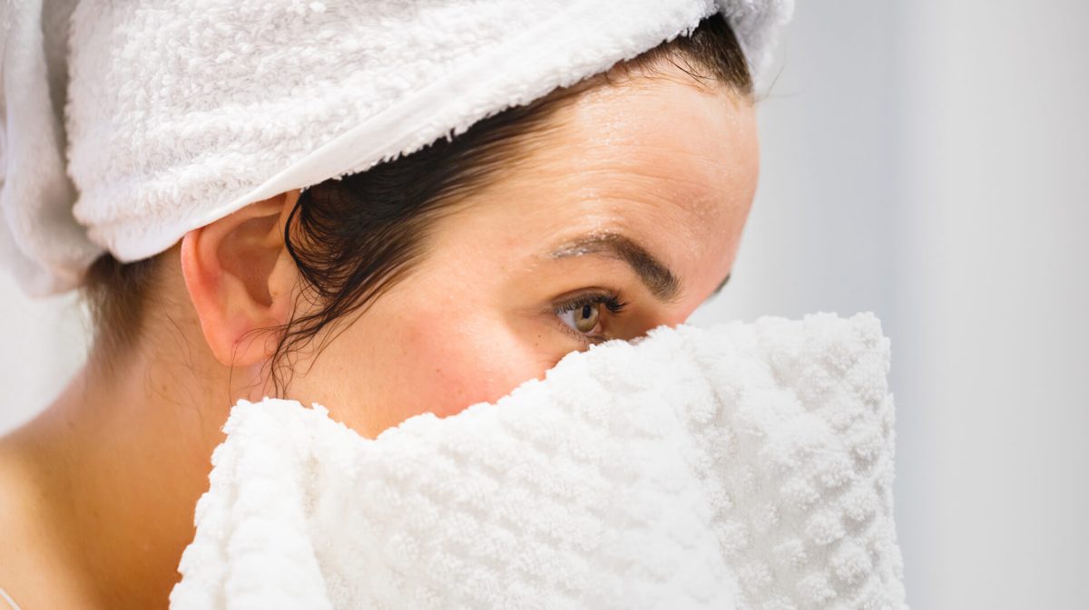 Frau trocknet sich Gesicht mit Handtuch ab