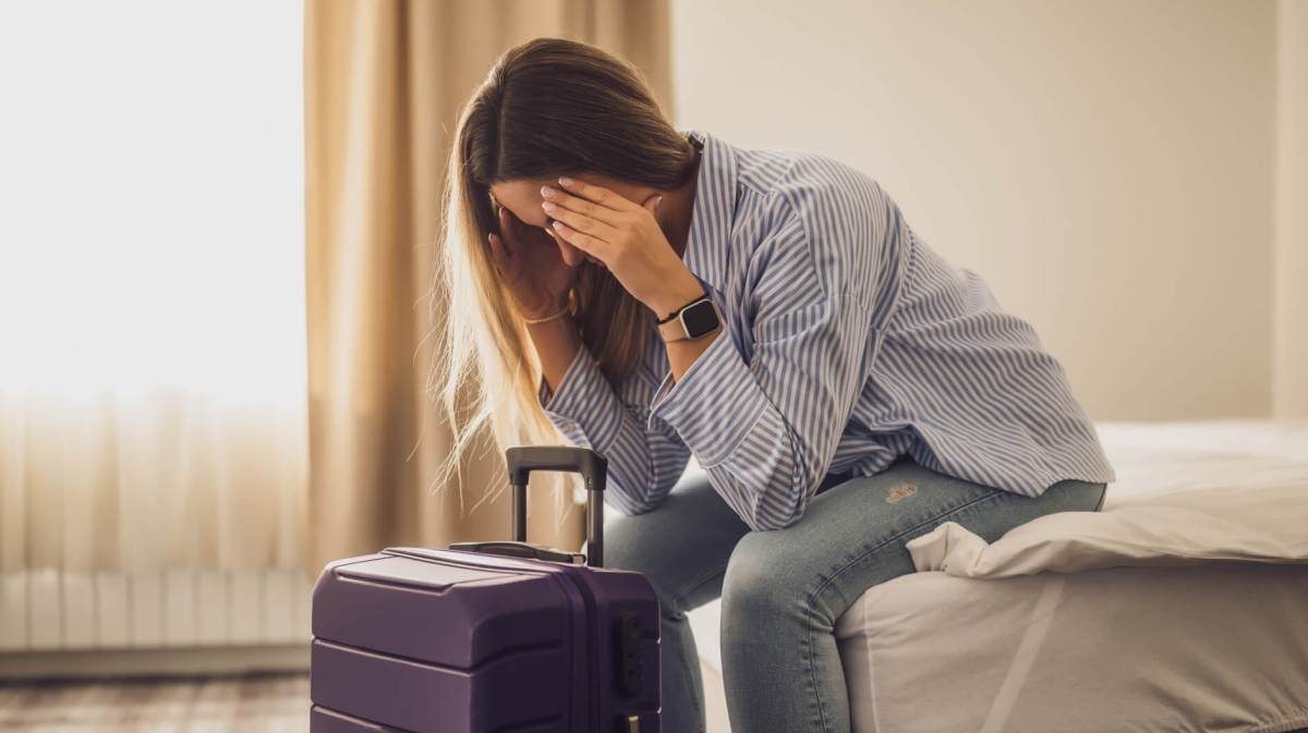 Frau sitzt im Hotelzimmer und hält sich die Hände vors Gesicht