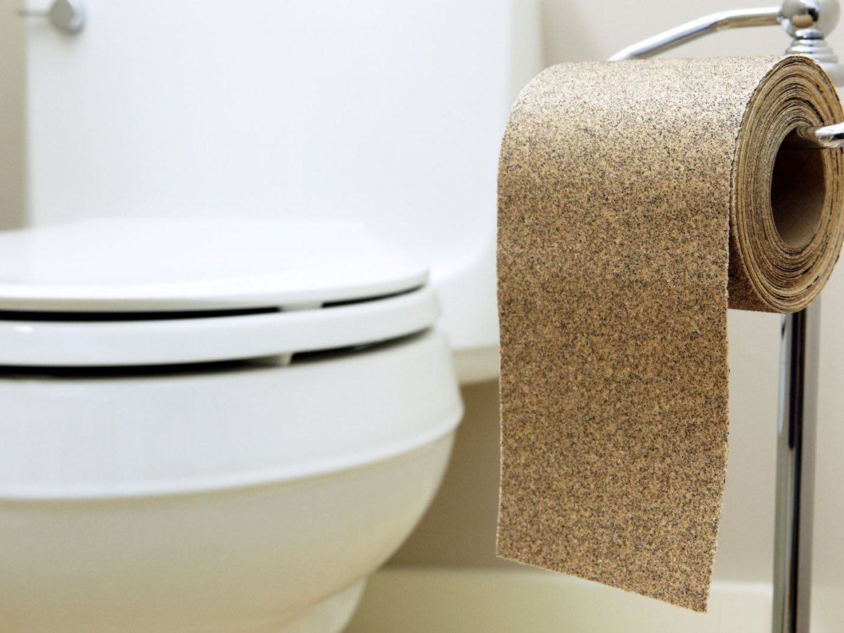 Toilette, daneben ein Klorollenständer mit einer Rolle Schleifpapier.