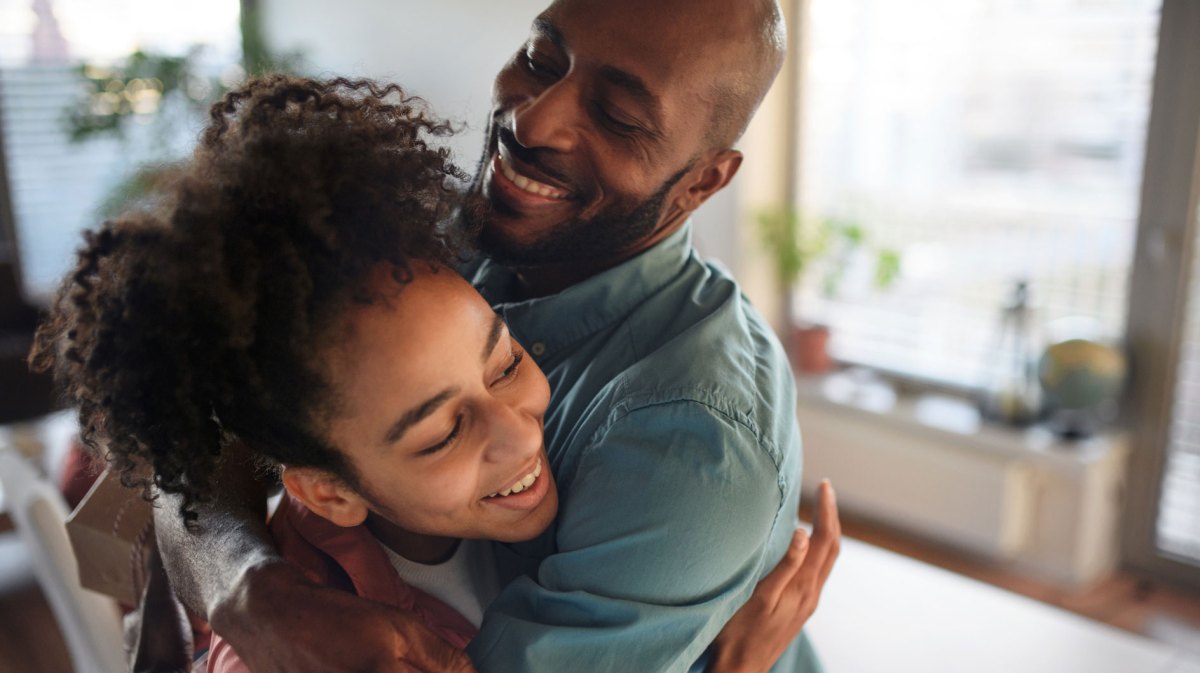 Tochter und Vater umarmen sich, beide lachen.