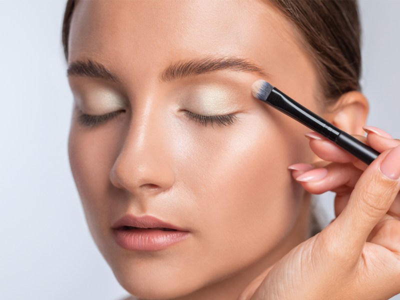 Frau, die gerade geschminkt wird und ein Augen-Make-up erhält.