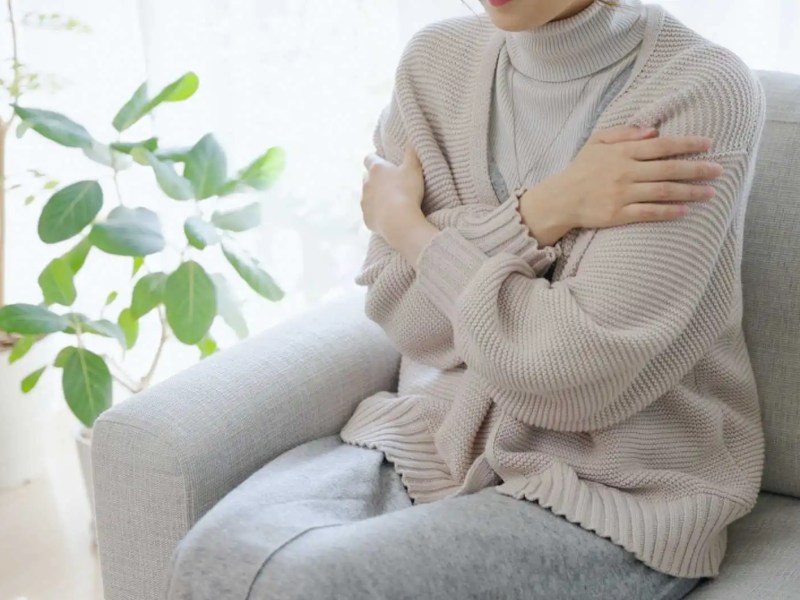 Frau sitzt auf dem Sofa und friert