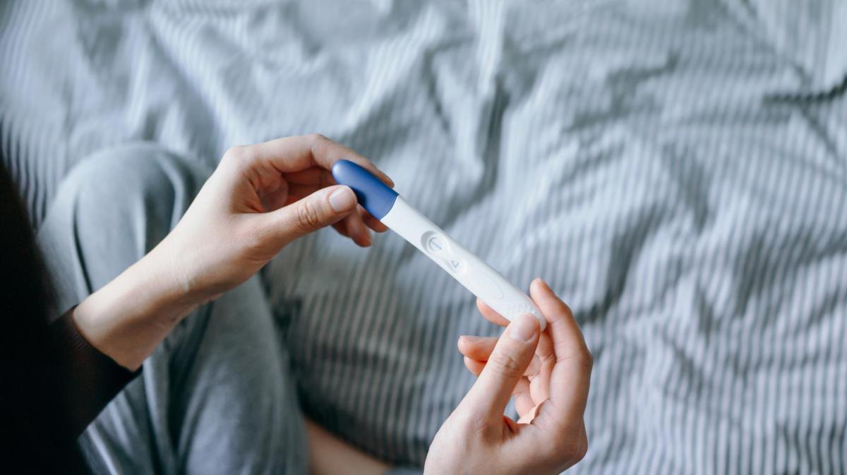 Frau hält einen negativen Schwangerschaftstest in der Hand.
