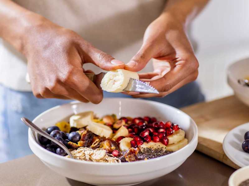 Nahaufnahme einer Frau, die sich einen gesunden Snack zubereitet.