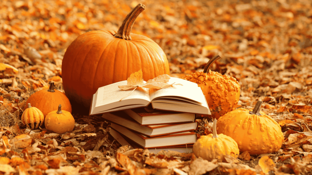 Bücherstapel und Kürbisse in Herbstlaub.