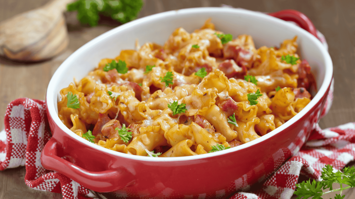 Nudelauflauf mit Schinken in einer roten Auflauflaufform.