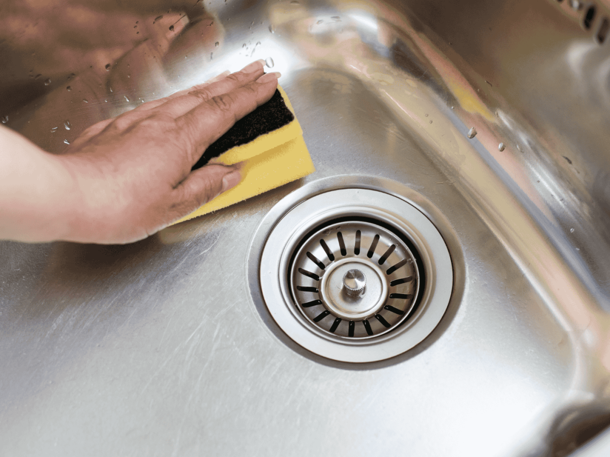 Person wischt mit Schwamm durch Spülbecken.