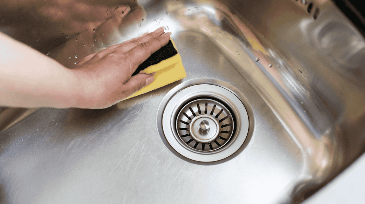 Person wischt mit Schwamm durch Spülbecken.