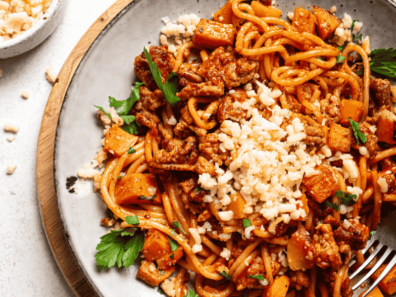 Spaghetti mit Kürbis-Bolognese auf hellem Teller.