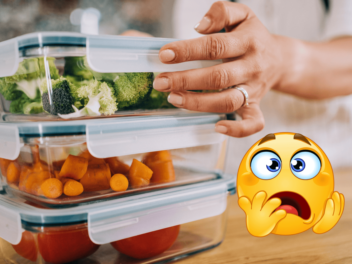 Nahaufnahme von Brokkoli, Karotten und Tomaten in Frischhaltedosen auf Holzoberfl&auml;che, gehalten von einer Hand mit Silberring und hellem Top.