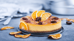 Orangen-Cheesecake mit Sternanis auf einem blauen Tischtuch.