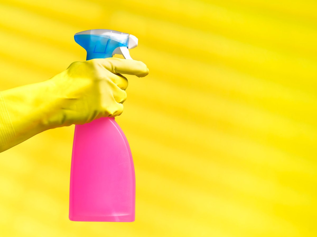 Hand in gelbem Gummihandschuh h&auml;lt Reiniger