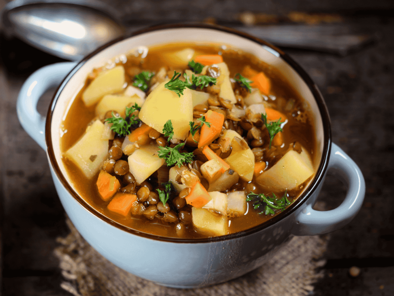 Linseneintopf mit Kartoffeln und Karotten in hellblauer Schüssel.
