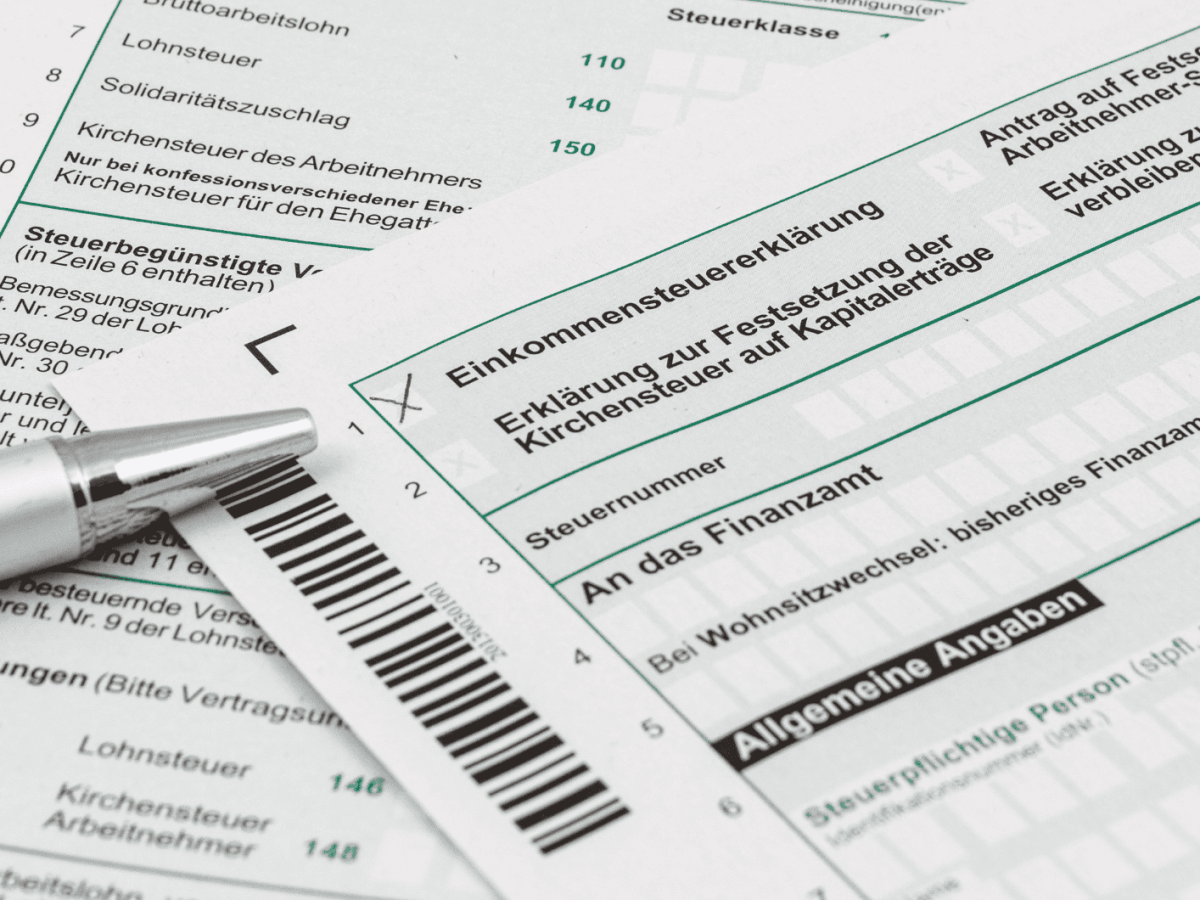 Steuerformulare liegen auf Tisch, ein Kulli daneben.