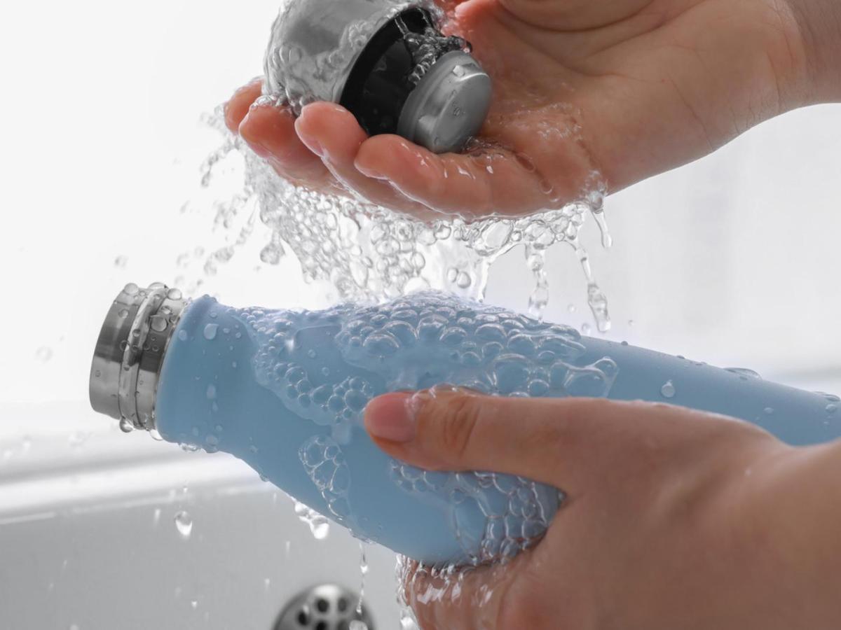 Frau sp&uuml;lt eine Thermoskanne mit Wasser aus.