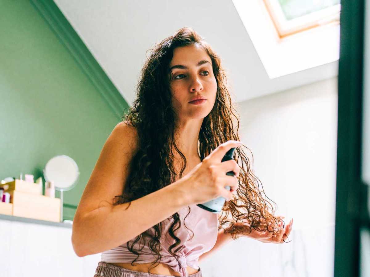 Frau sprüht sich etwas in ihre frisch gewaschenen Haare.