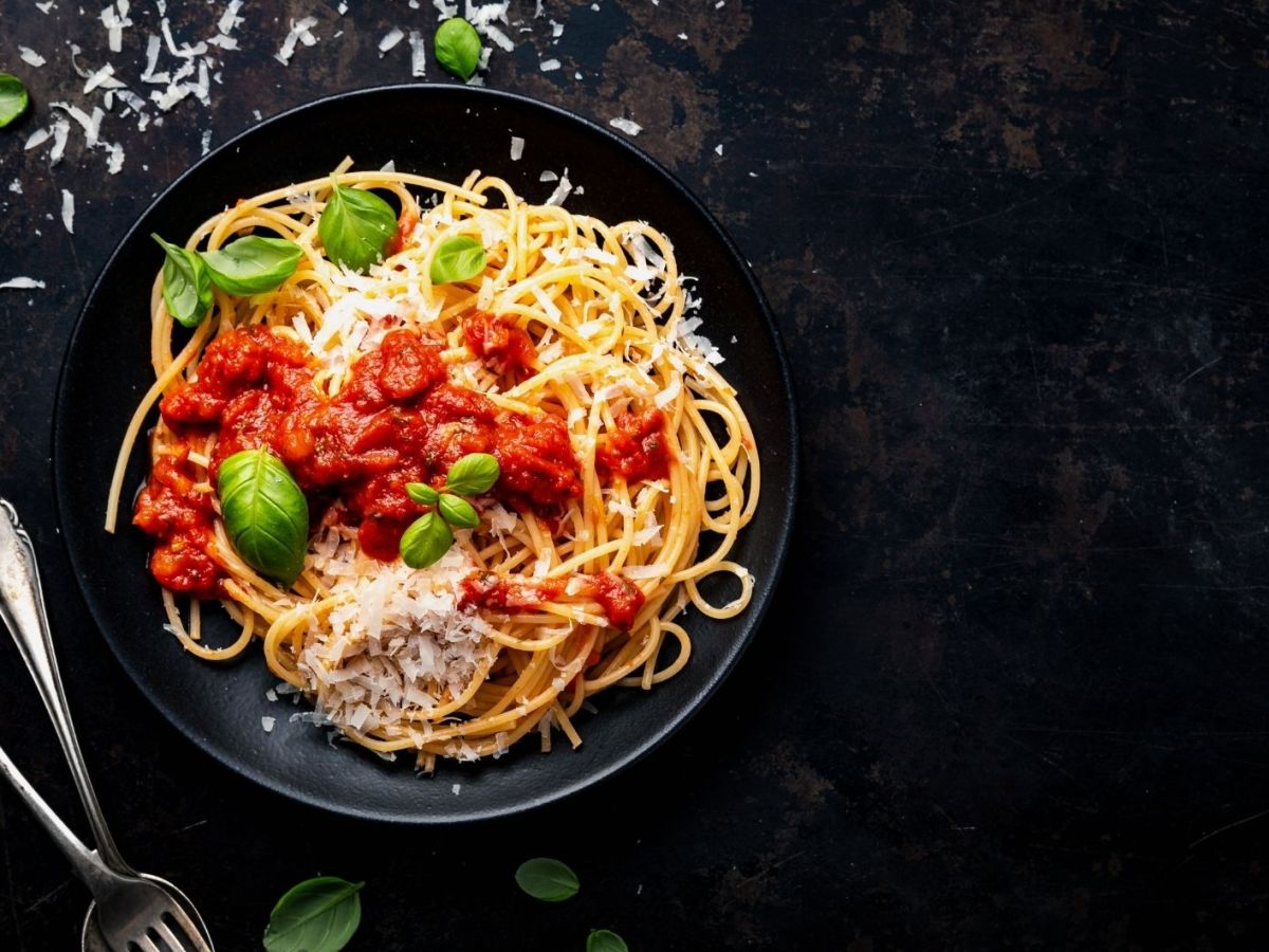 Spaghetti mit Tomatensauce, Basilikum und Parmesan auf schwarzem Hintergrund