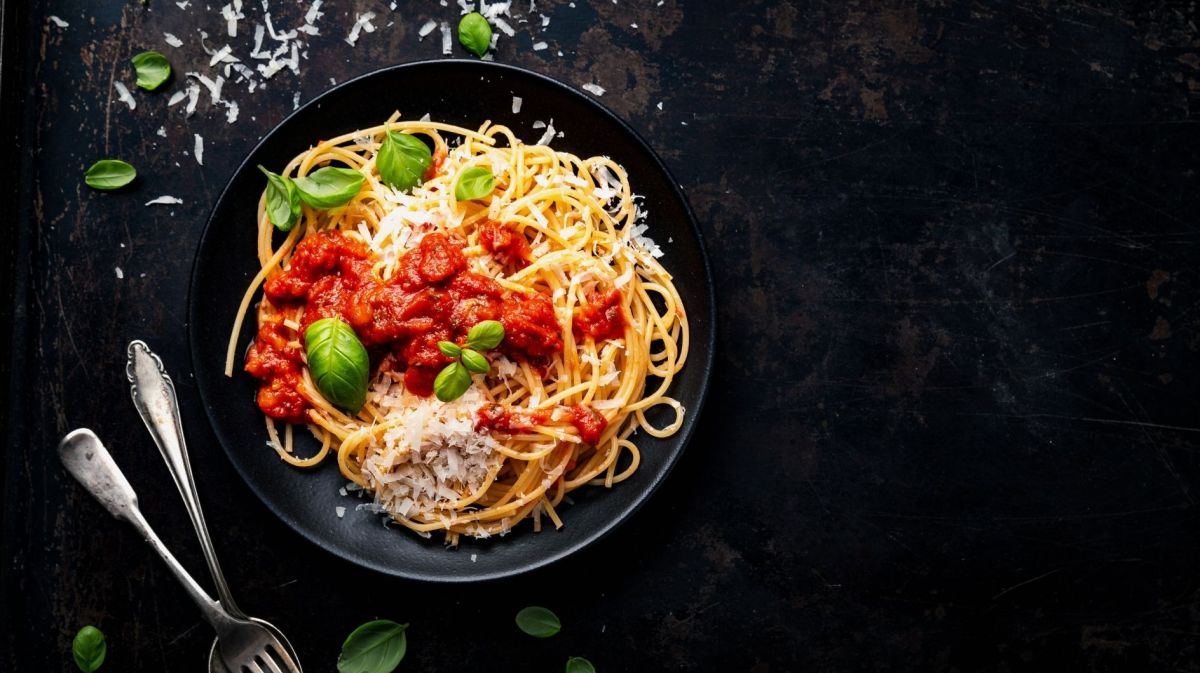 Spaghetti mit Tomatensauce, Basilikum und Parmesan auf schwarzem Hintergrund