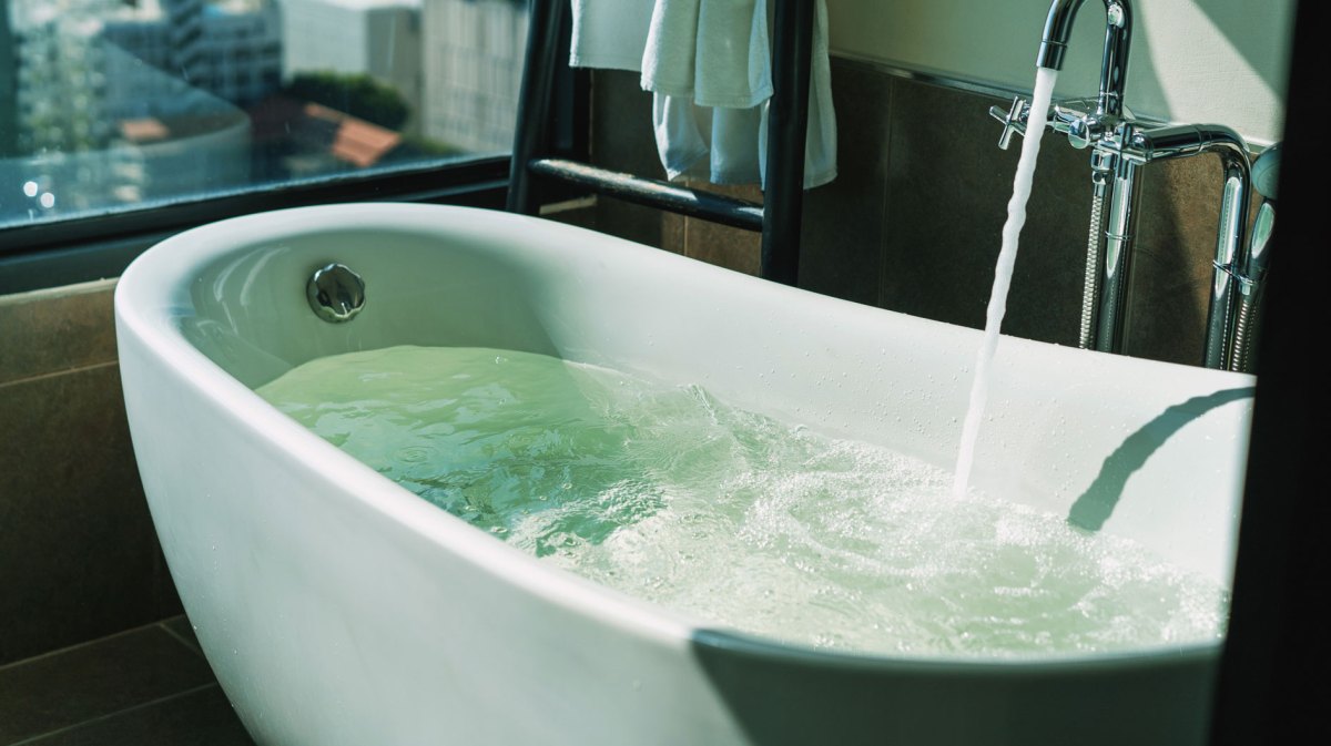 Badewanne, direkt am Fenster, in die Wasser einläuft.