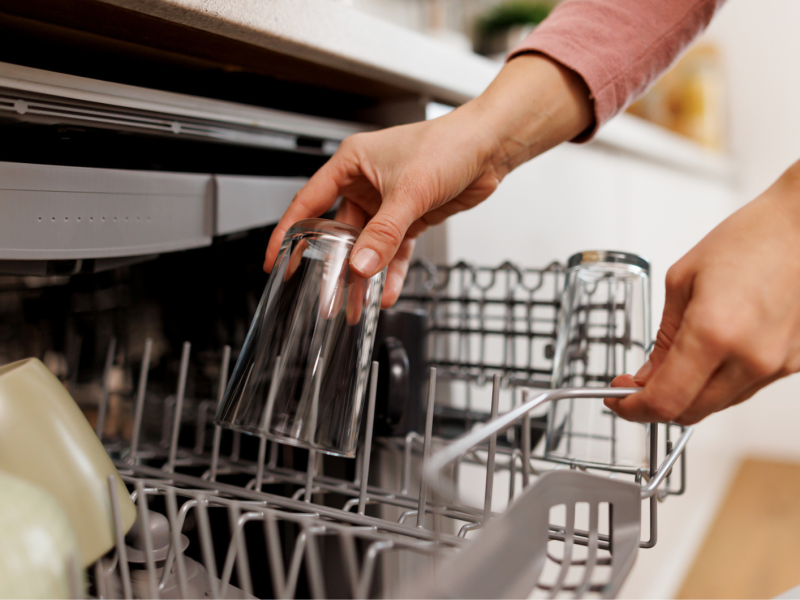 Frau räumt Geschirr ein.