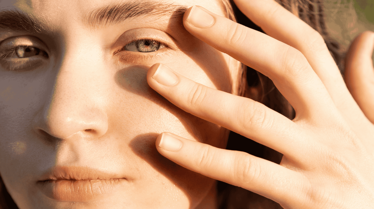 Eine junge Frau hält ihre Hand ans Gesicht.