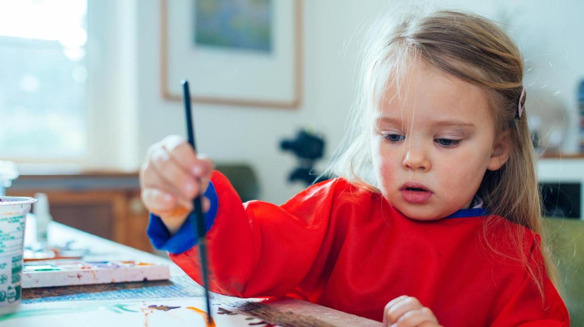 Kleines Mädchen mal mit einem Pinsel.