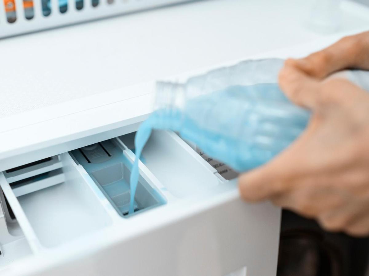 Frau f&uuml;llt einen Reiniger in das Hauptfach der Waschmaschine.