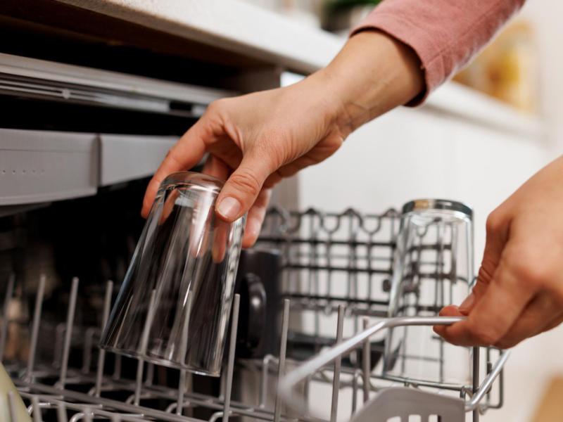 Frau räumt ein Glas aus der Spülmaschine.