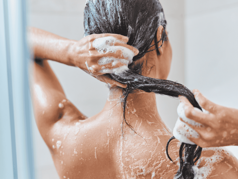 Frau wäscht ihre Haare nach Shampoo aus.