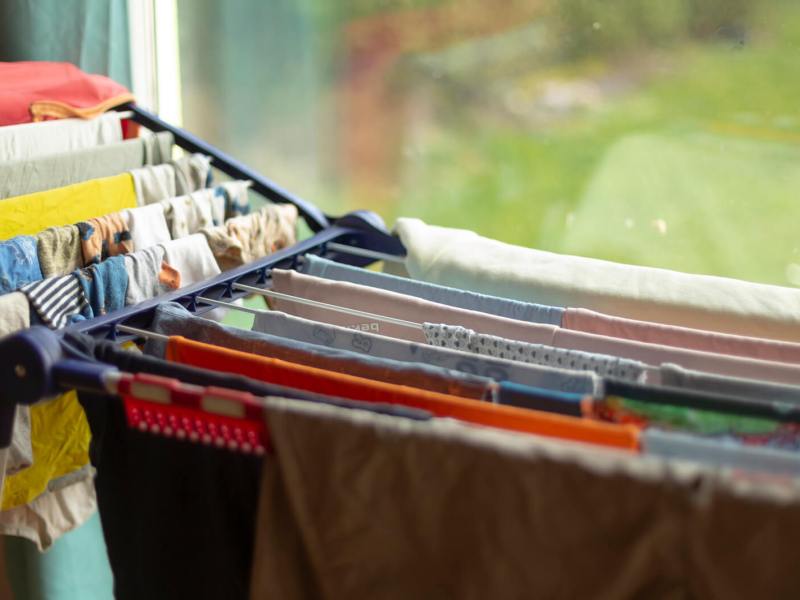 Wäscheständer mit bunter Kleidung steht in einer Wohnung