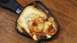 Raclette-Pfännchen mit Käse und Fleisch.