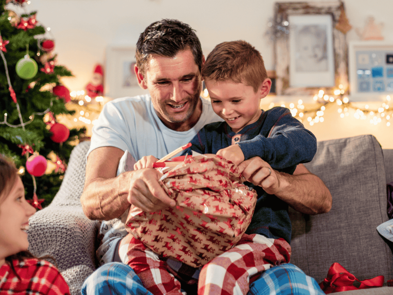 Ein Vater packt an Weihnachten ein Geschenk mit seinem Sohn aus.