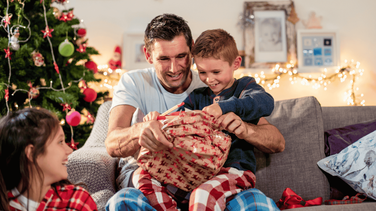 Ein Vater packt an Weihnachten ein Geschenk mit seinem Sohn aus.