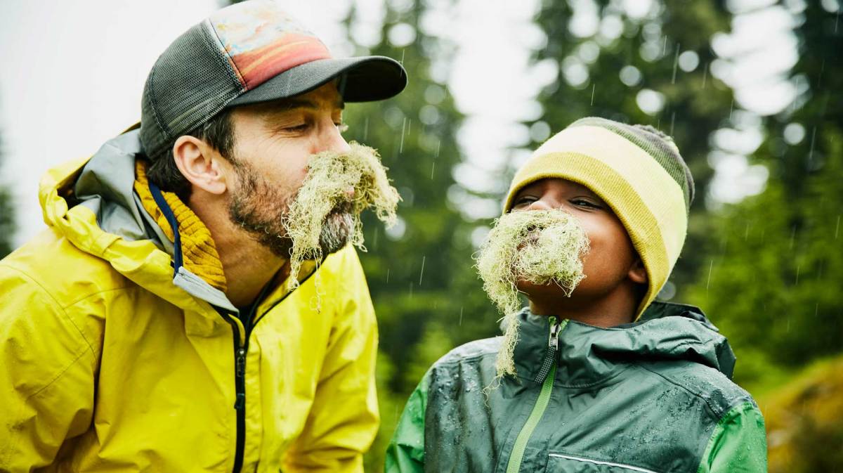 Vater und Sohn albern herum und haben sich mit Naturmaterialien einen Bart gebastelt.