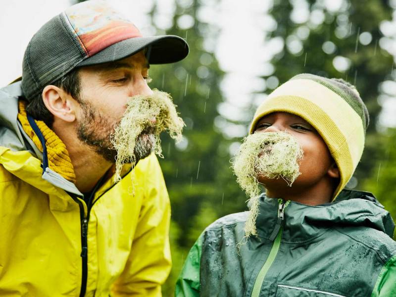 Vater und Sohn albern herum und haben sich mit Naturmaterialien einen Bart gebastelt.