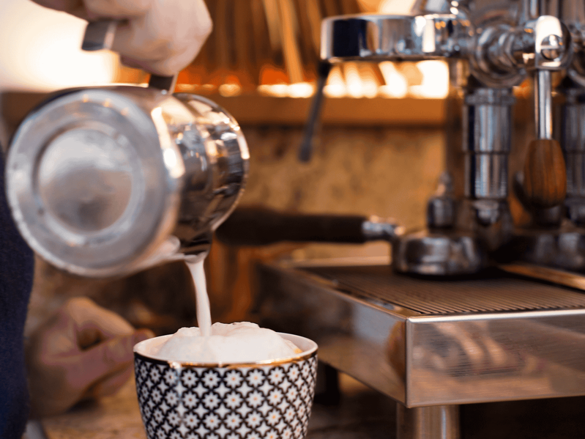 Milchschaum wird in eine bunte Tasse gegossen