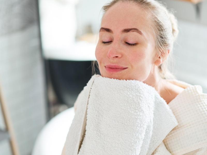 Frau reibt ihr Gesicht an ein Handtuch.