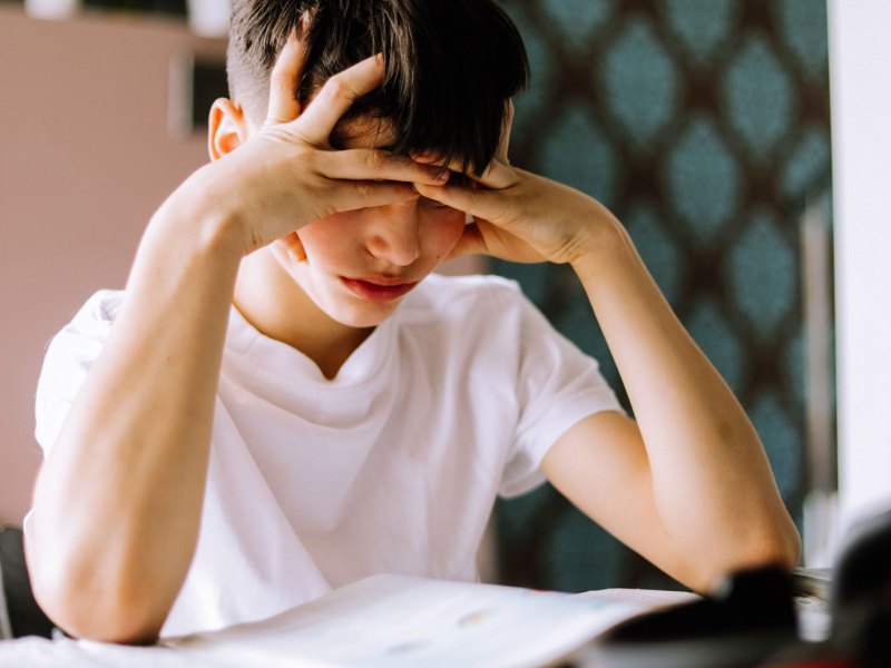 Junge, ca. 12 Jahre, schaut verzweifelt auf seine Hausaufgaben.