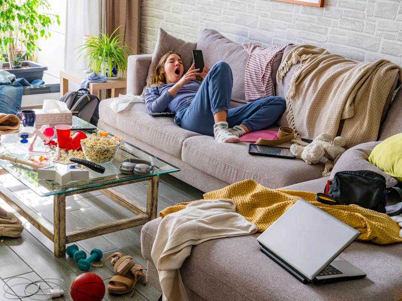 Teenagermädchen liegt auf dem Sofa, um sie herum herrscht Chaos.
